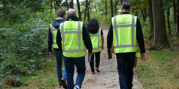 people walking in a forest with safety jackets